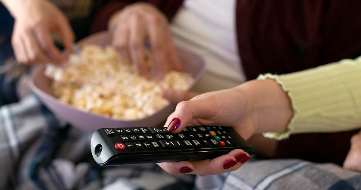 Eating popcorn and holding a remote control